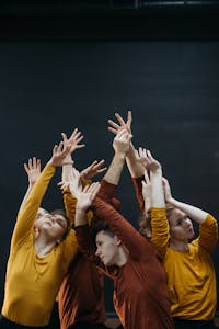 Creative dancers practicing choreography together with raised arms indoors.