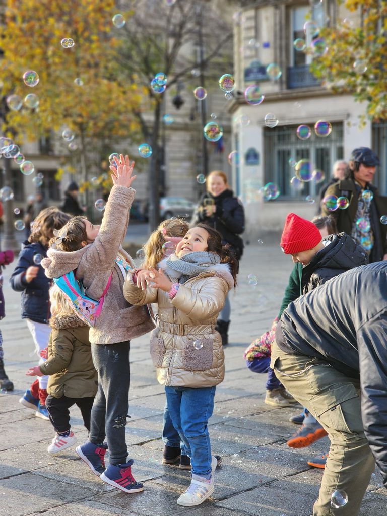 Kids having fun with bubbles on a lively city street in autumn.