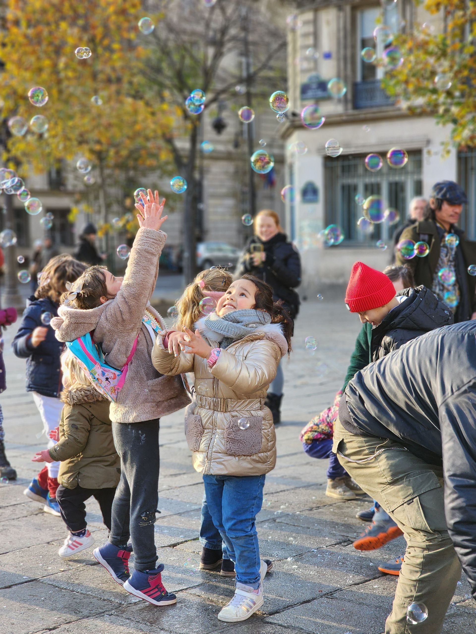 Kids having fun with bubbles on a lively city street in autumn.