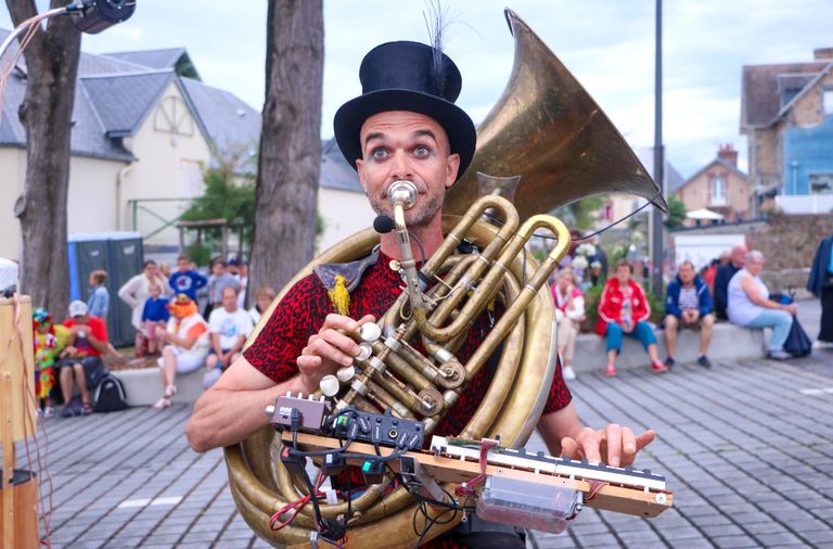 Street performer with a sousaphone entertaining in a lively outdoor setting in Saint-Pair-sur-Mer, Normandie, France.