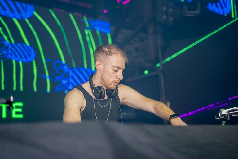 DJ immersed in music at a nightclub with colorful neon lighting, creating an energetic vibe.
