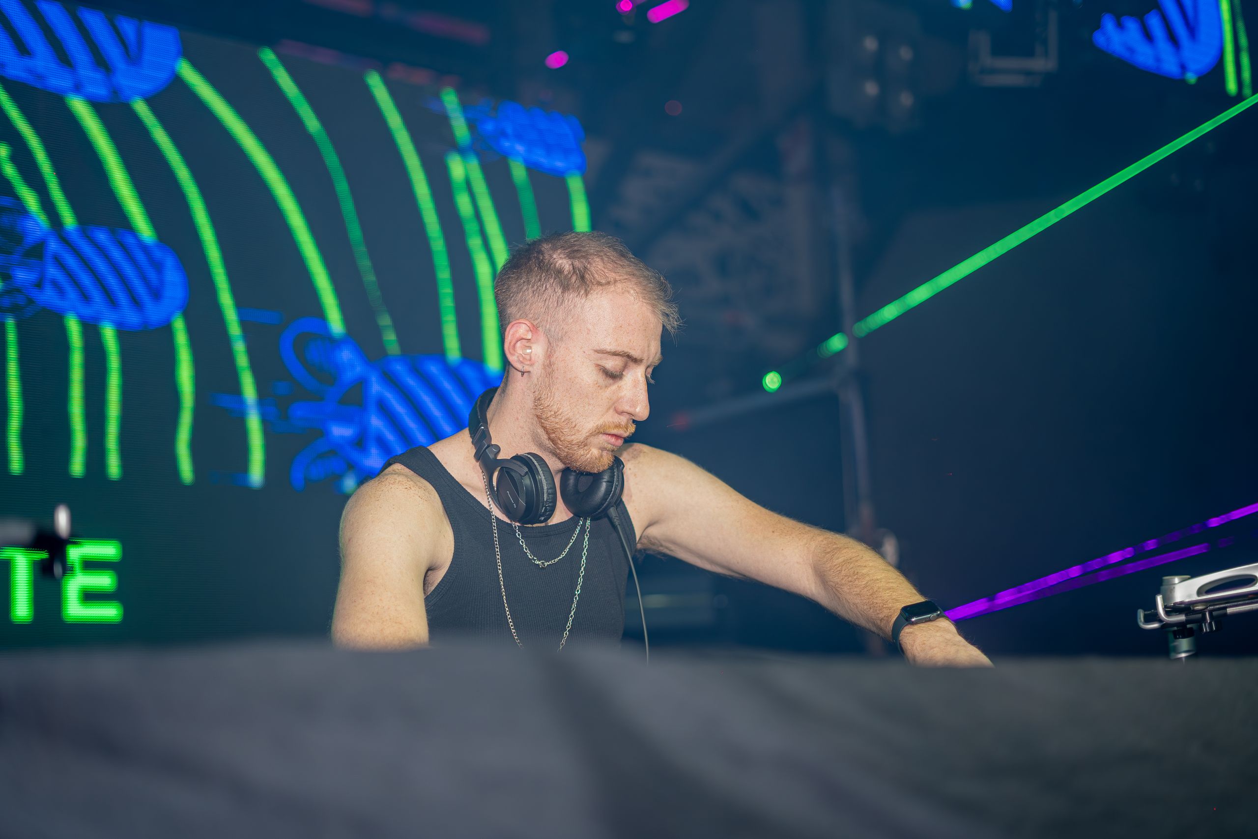 DJ immersed in music at a nightclub with colorful neon lighting, creating an energetic vibe.