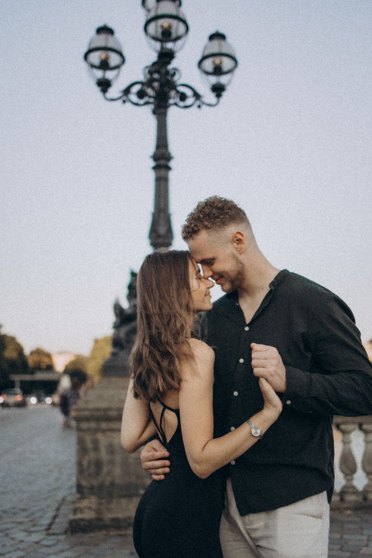 A loving couple shares an intimate moment outdoors by a streetlamp.