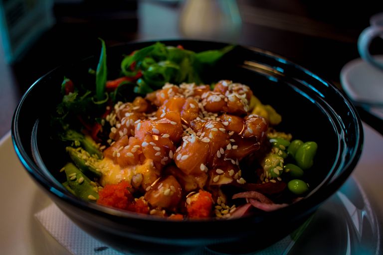 Close-up of a mouthwatering poke bowl with salmon, avocado, and sesame seeds.