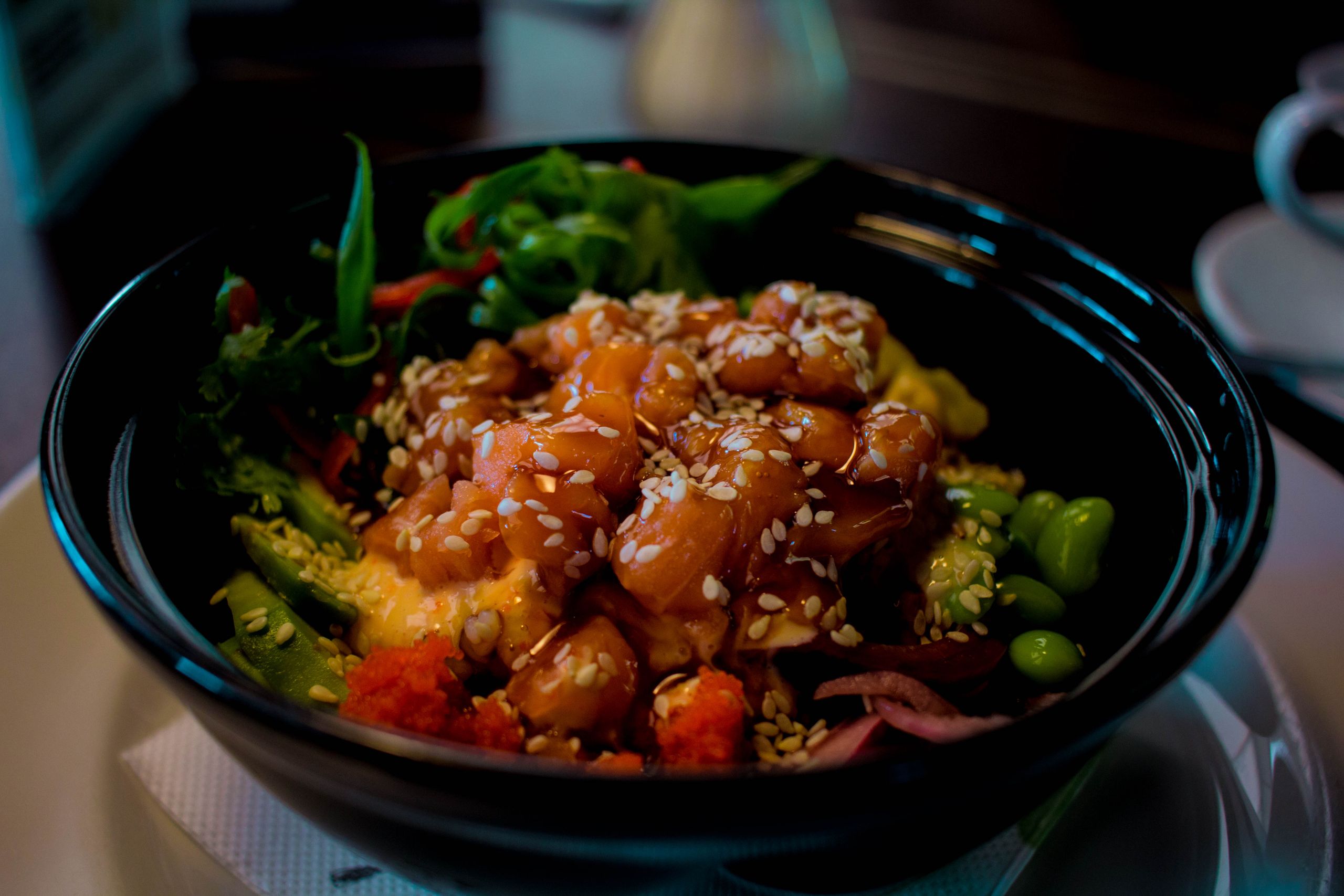 Close-up of a mouthwatering poke bowl with salmon, avocado, and sesame seeds.