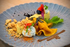 Delicately presented gourmet dish with vibrant colors and artistic flair on a textured plate.