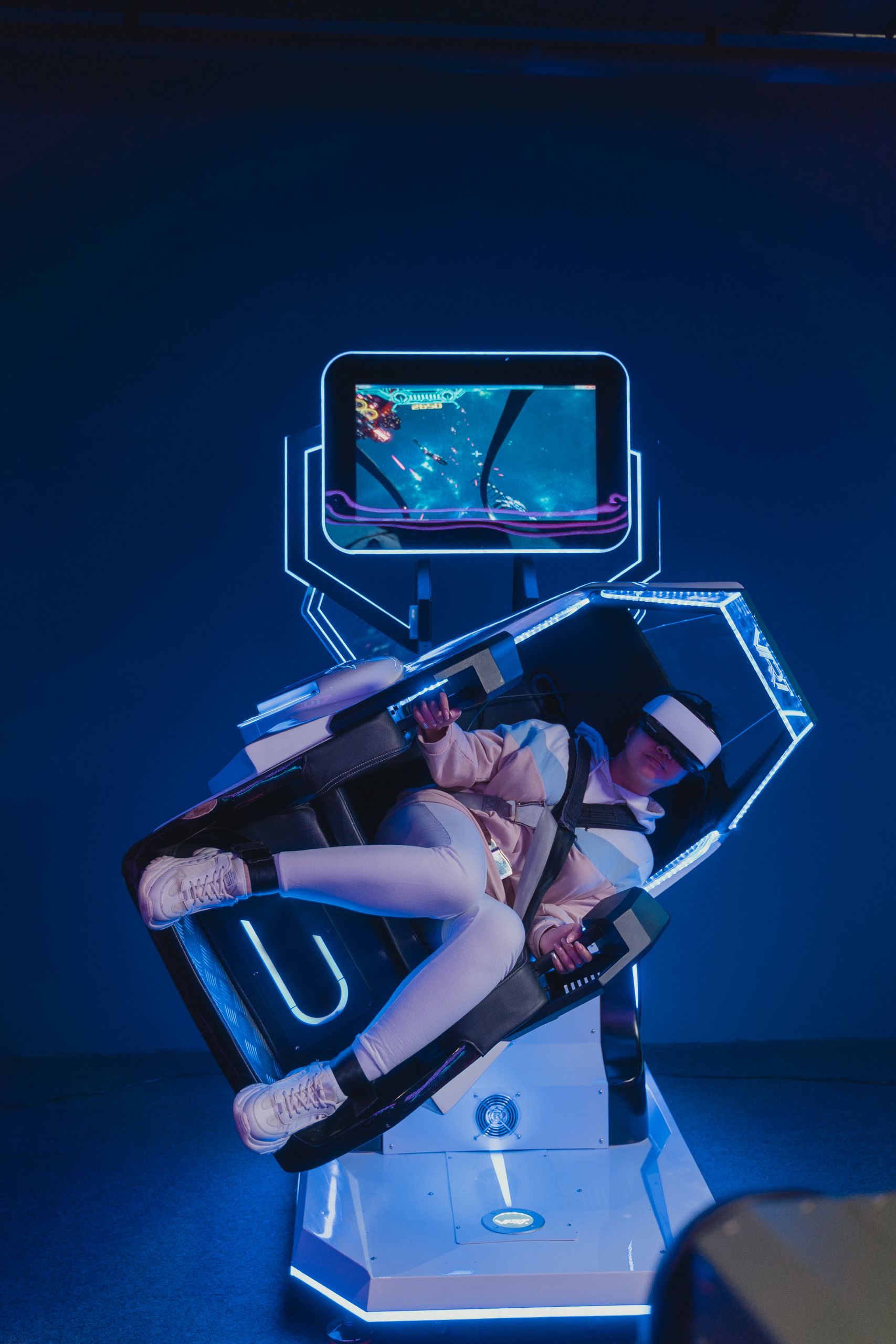 Person enjoying a futuristic virtual reality gaming simulator indoors with neon lights.